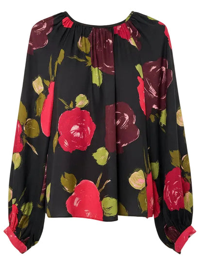 Black blouse with red and green floral pattern on a hanger against a white background