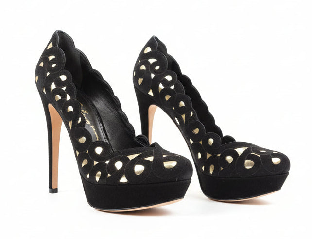Black high-heeled shoes with cut-out design on a white surface.