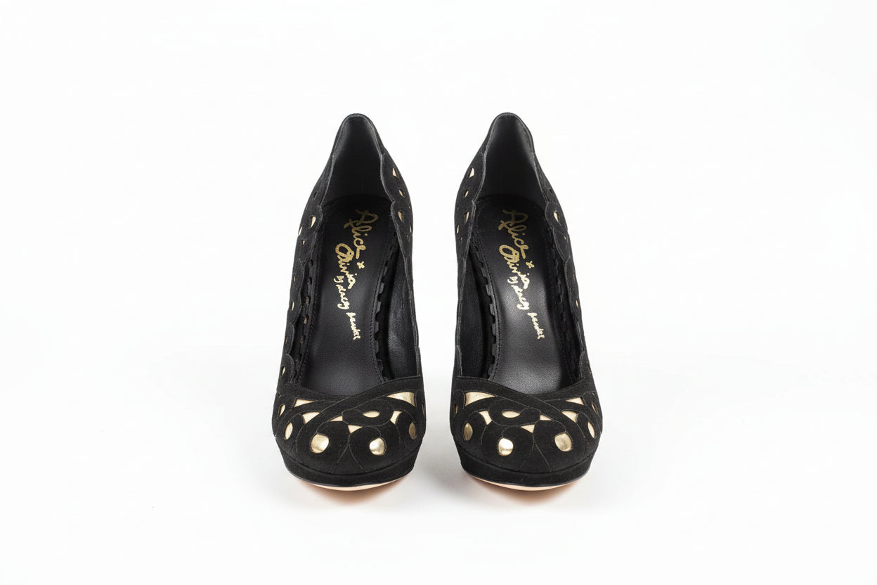 Black high-heeled shoes with gold heart designs on a white surface