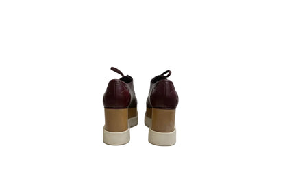 Pair of brown leather shoes with beige soles on a white surface.