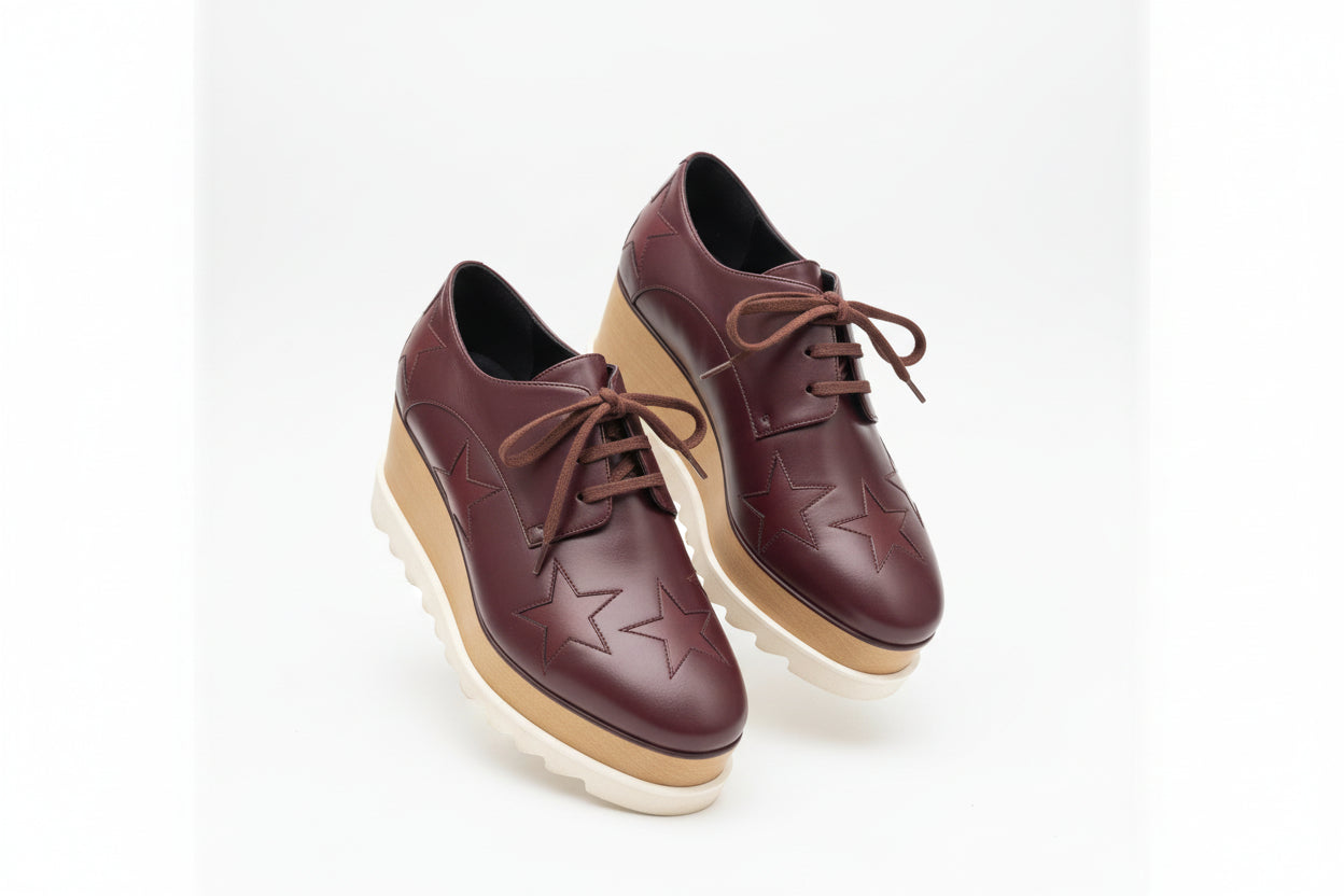 Pair of maroon shoes with star patterns on a white background