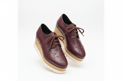 Pair of maroon shoes with star patterns on a white background
