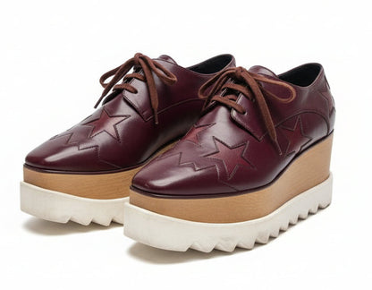 Brown leather shoes with star design and platform sole on a white background