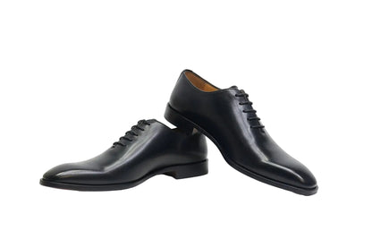 Black leather dress shoes with brown soles on a white background